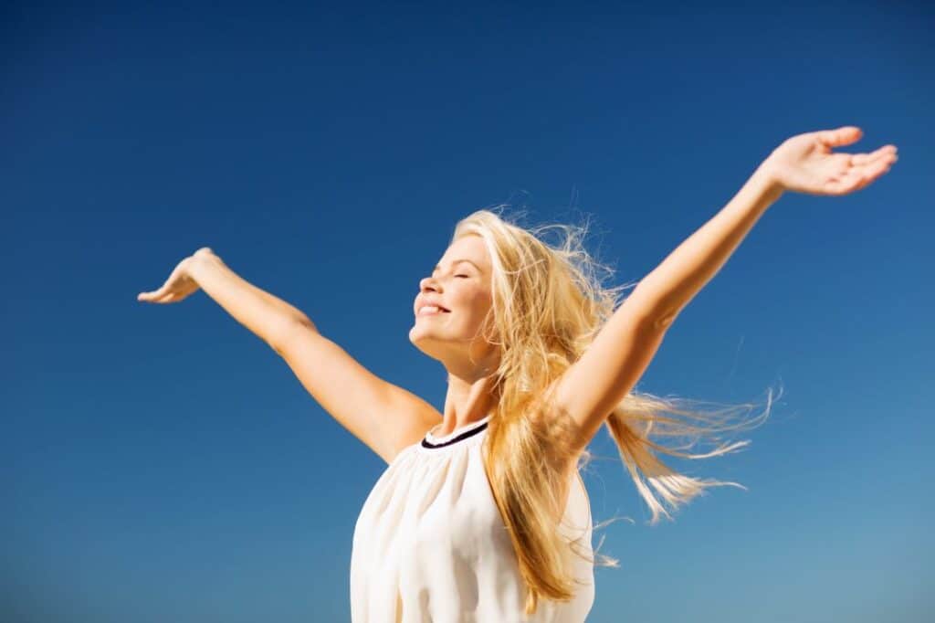 a woman smiling while raising her hands up towards the sky