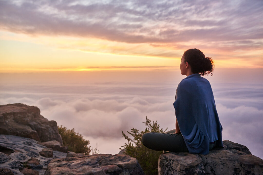 a woman sitting peacefully on a mountain