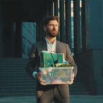 Sad office worker man walking with box of personal stuff lose a job