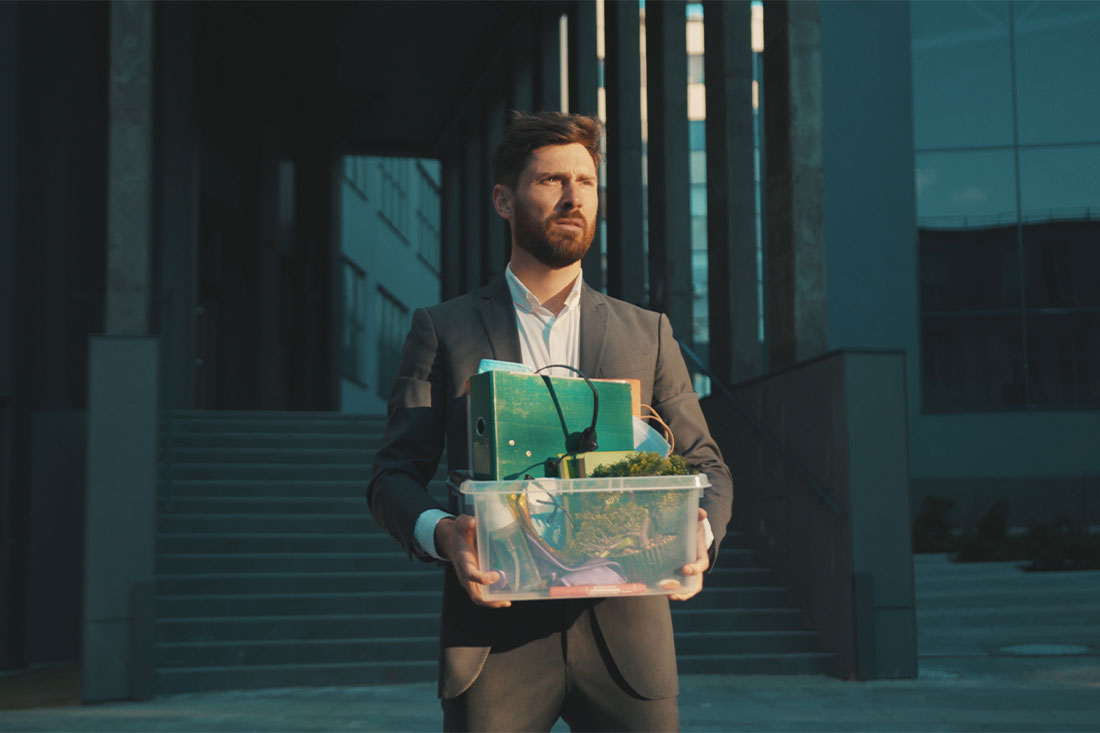 Sad office worker man walking with box of personal stuff lose a job