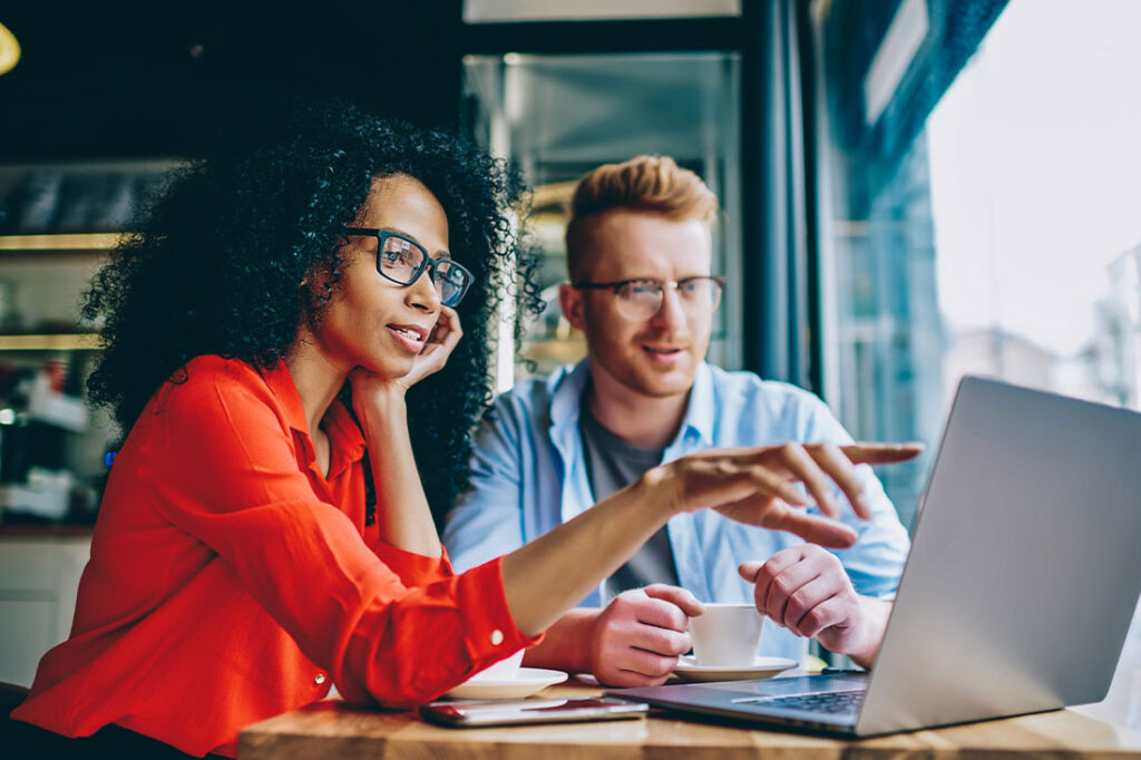 female pointing with finger on laptop computer during collaboration with male colleague