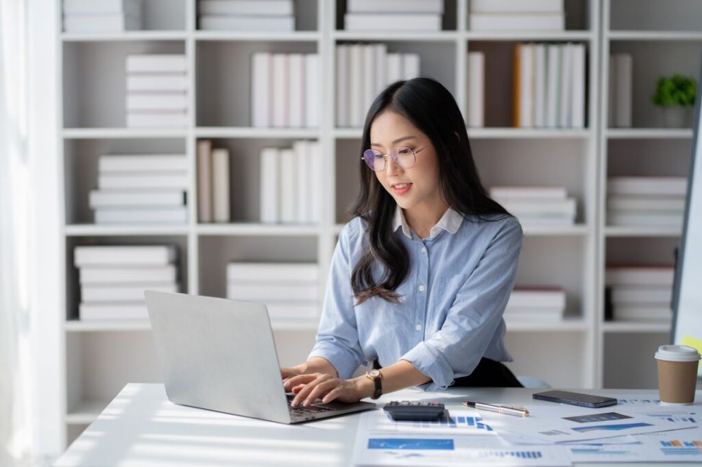 a woman sitting at a desk in an office and doing work on a laptop