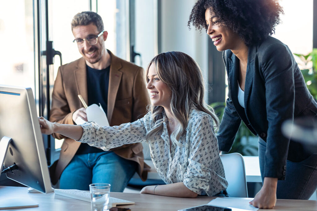 Shot of successful business multiage team standing around computer for presentation of work in the coworking space