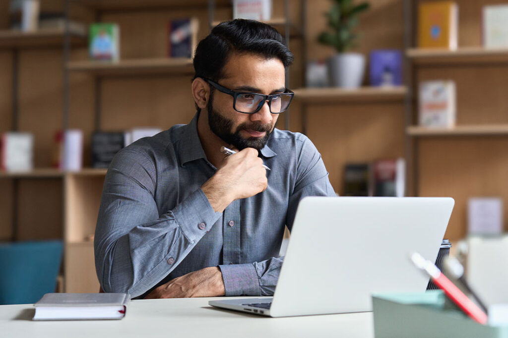 Young professional business man, focused wearing glasses working on laptop