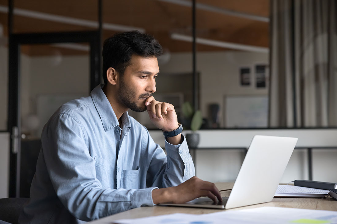 man working at laptop, sitting at workplace table