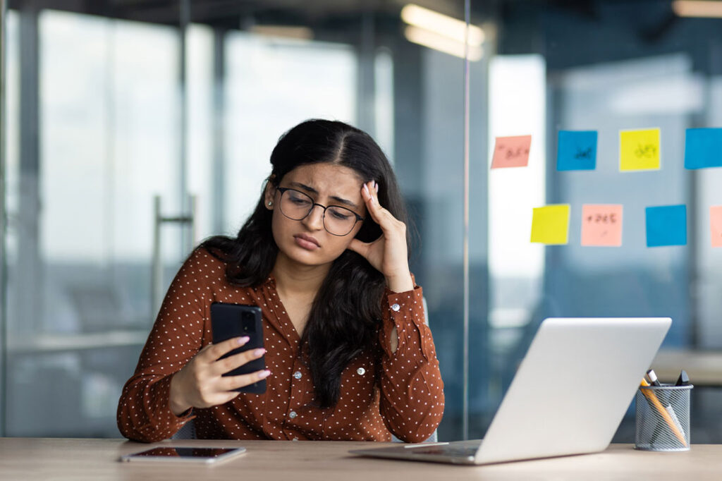 A worried business woman holding phone in her hands at the office