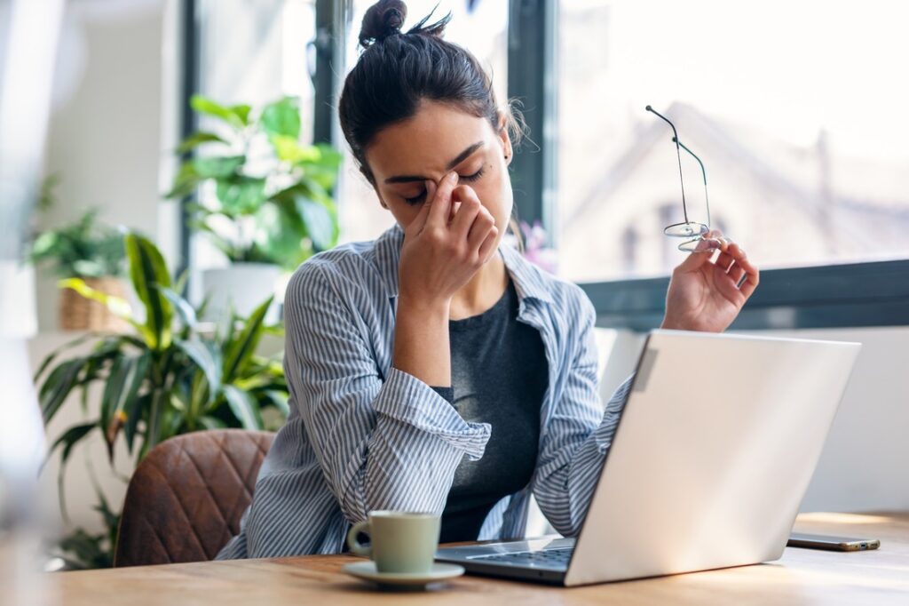 A woman sitting at a desk looking stressed while working