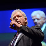 Leadership professor and former hostage negotiator George Kohlrieser speaks on stage at an event, teaching audiences how to negotiate