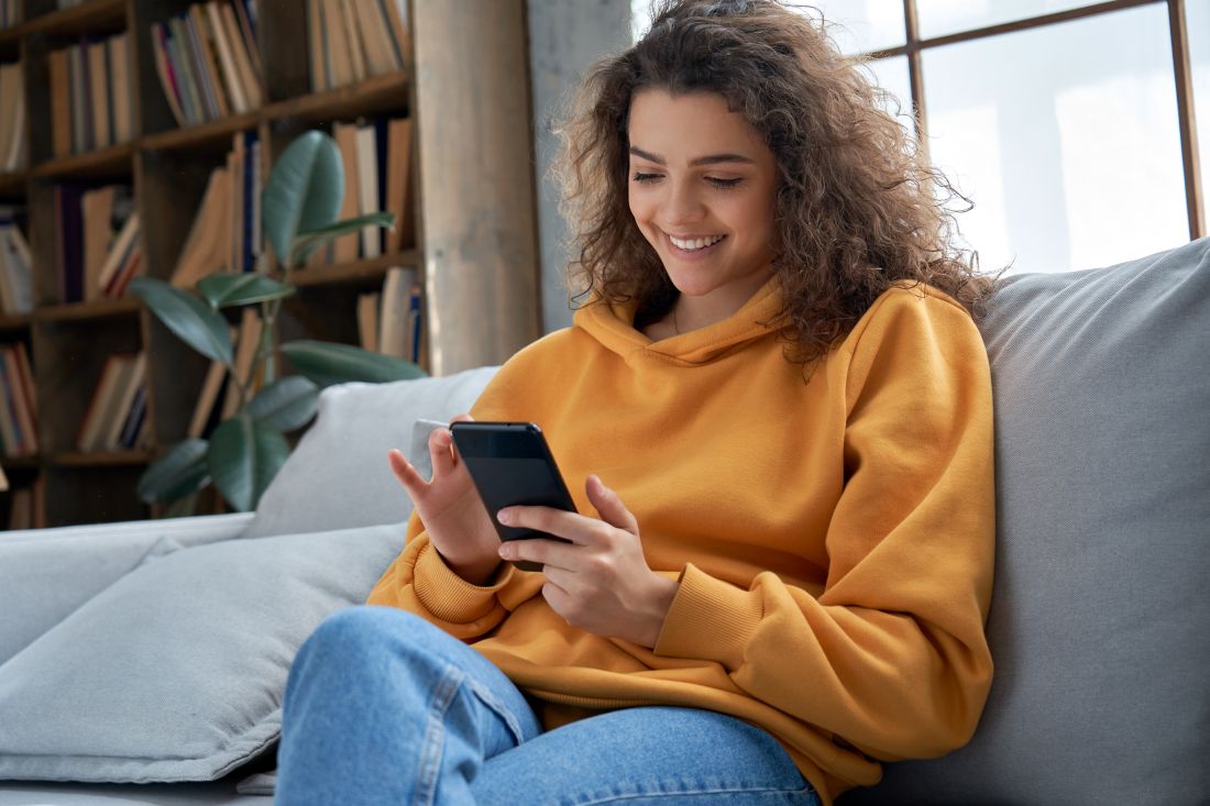 woman sitting on a couch scrolling through her phone