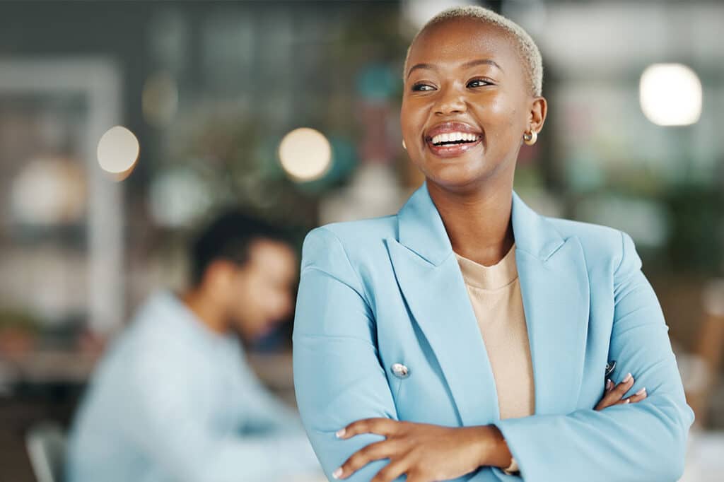 black woman with smile and arms crossed in office