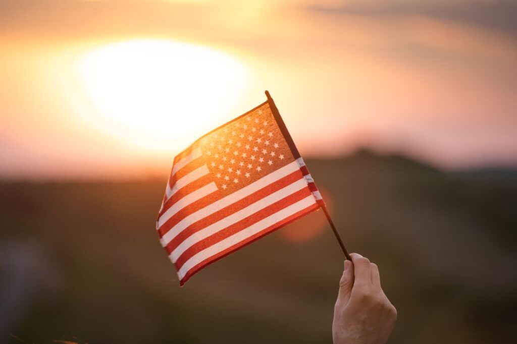 person holding the American flag with a sunset in the background