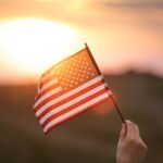 person holding the American flag with a sunset in the background