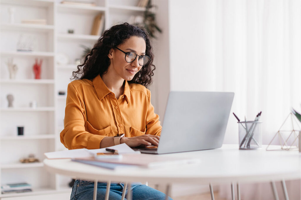 Woman Using Laptop Working Online in Office