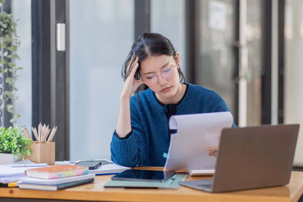 tired young business woman working with documents and laptop