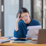tired young business woman working with documents and laptop