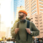 Man in city smiles and wears a backpack while on a miro-retirement trip