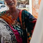 A woman dressed in a sari looks at hanging fabric.