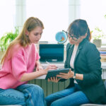 College counselor talking with teenage girl, using digital tablet for work