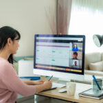 woman in pink shirt sitting at computer on a conference call