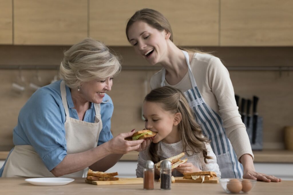 A woman making sandwiches with her mother and daughter.