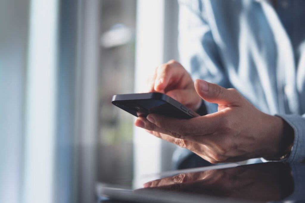 Close up of hands holding a cell phone.