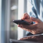 Close up of hands holding a cell phone.