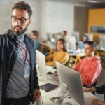 A teacher gives a lecture to rows of students at computers.