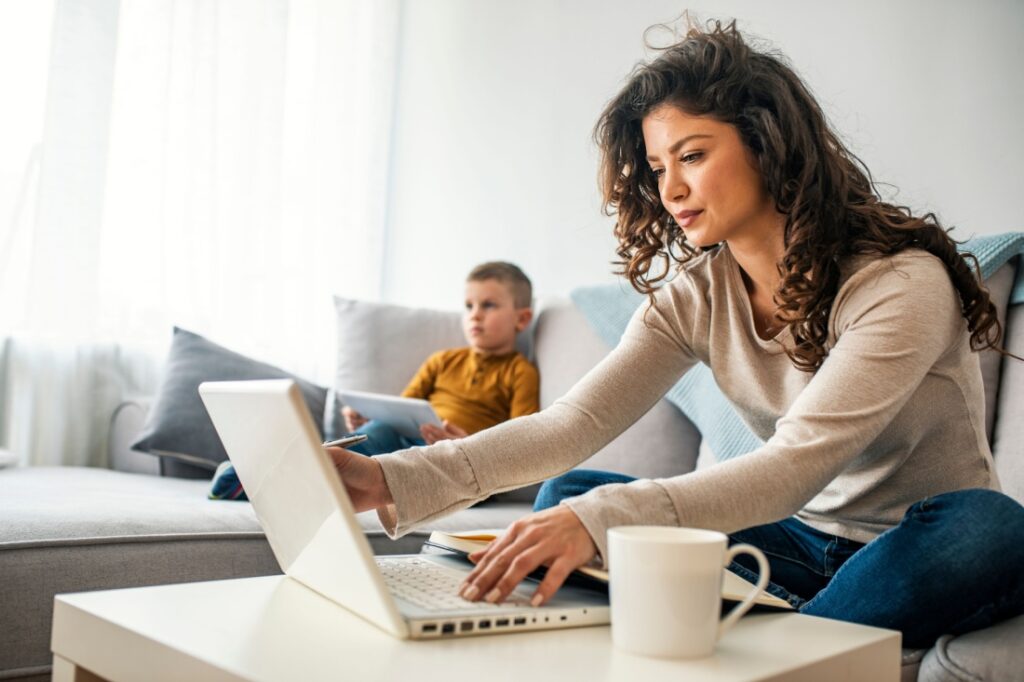 A woman writing on her laptop from a couch.