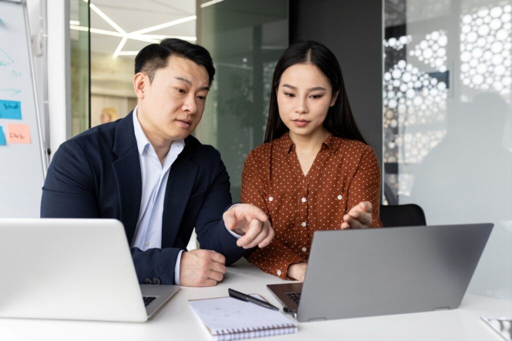 A man and woman point at a computer screen.
