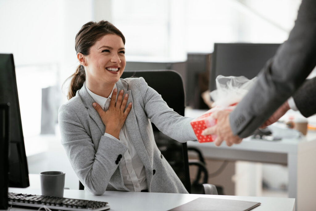 A woman happily accepting a gift from a colleague at work
