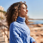 Young hispanic woman in blue sweater smiling