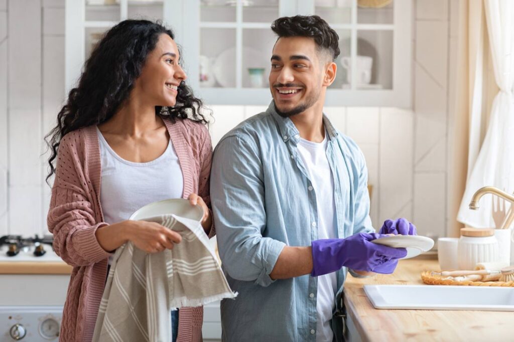 Husband and wife washing and drying dishes together