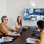 Employees having an in-person business meeting with some staff attending remotely