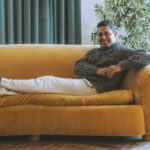 Wilmer Valderrama sitting on a brown couch