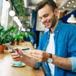 young smiling man with credit card and phone in hands